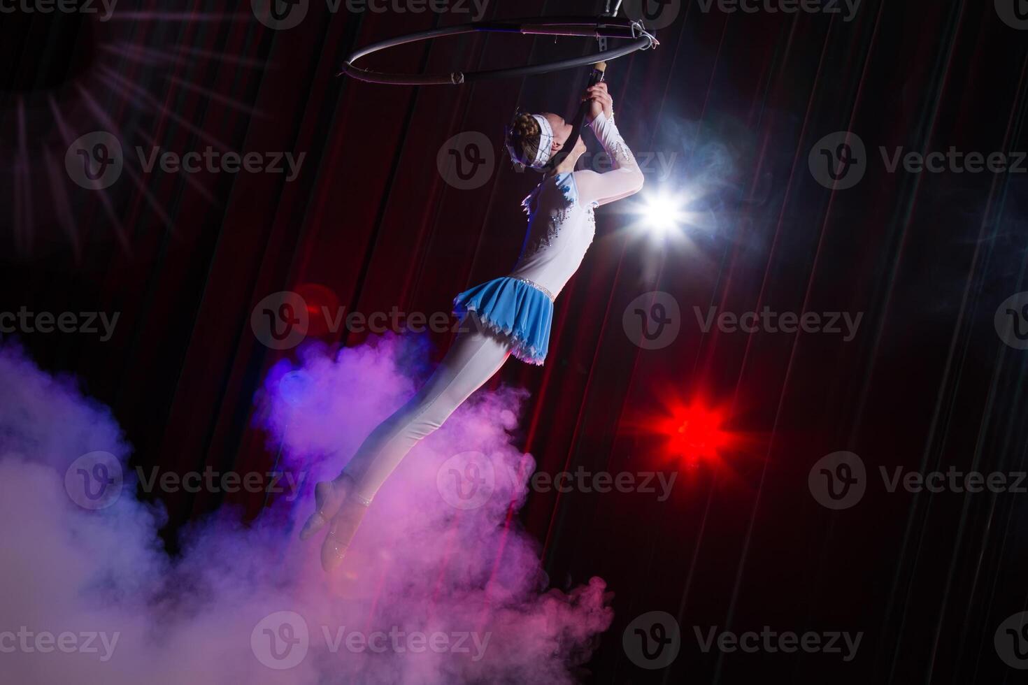 Performs a circus girl actress. Circus aerial gymnast on the hoop. Acrobatics. Teenager performs an acrobatic trick in the air photo