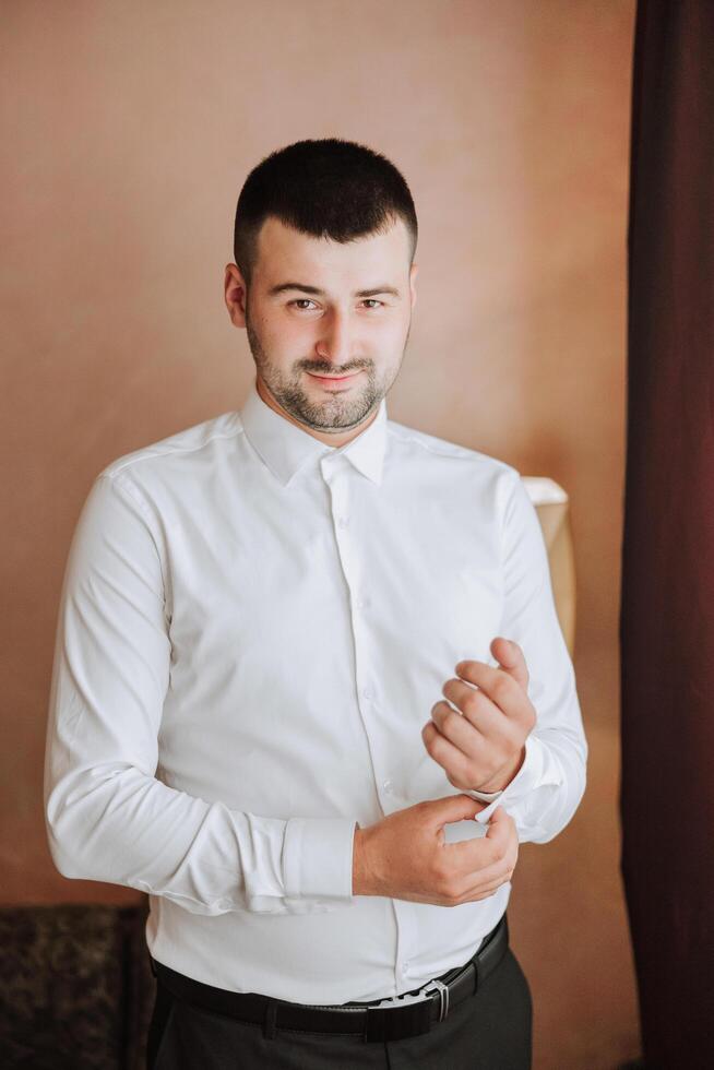 Business shirt. A man in a white shirt fastens the buttons. Young politician, male style, businessman buttoning shirt, male hands close-up, american, european businessman photo