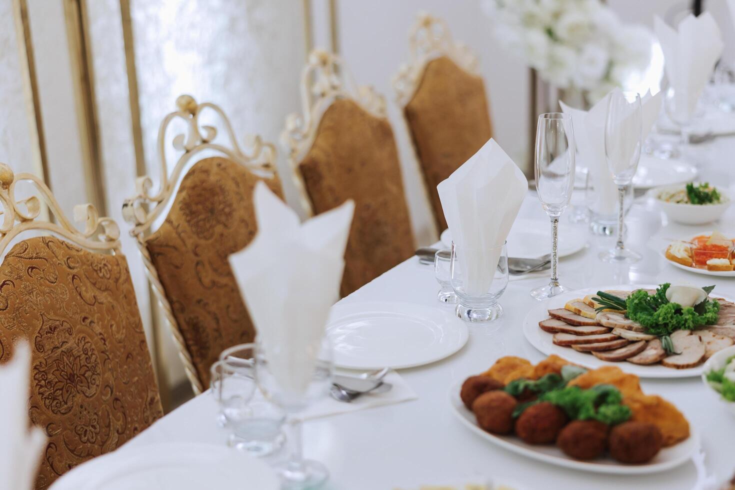 A view of wedding tables, attention to serving, with flower arrangements, expensive cutlery, plates with white napkins. photo