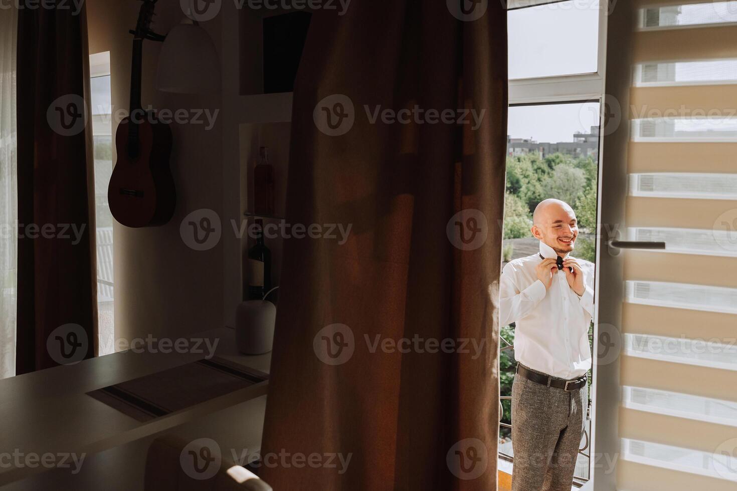 man in shirt dressing up and adjusting tie on neck at home. Wedding day concept,fashion, business, male style. photo