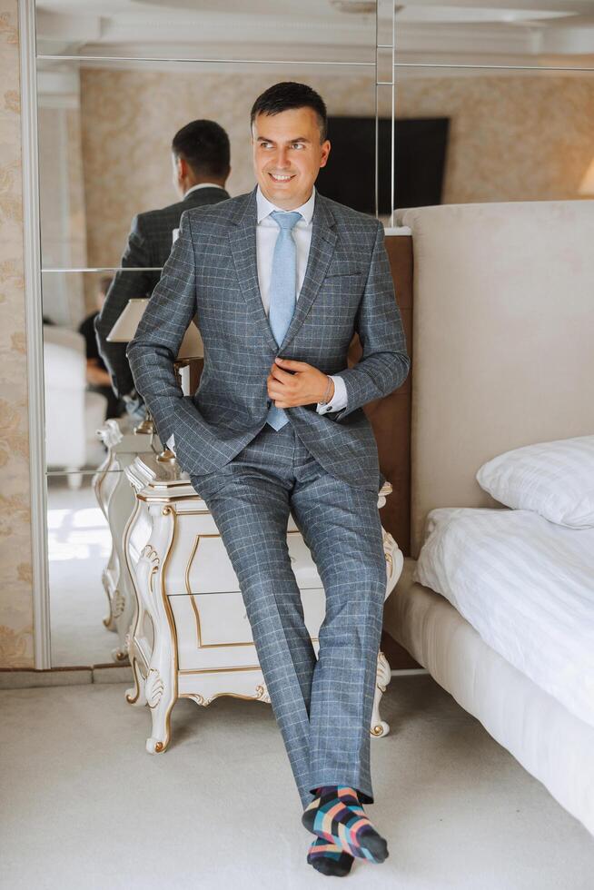 Portrait of a young groom at home before the wedding ceremony. A handsome man dressed in a classic suit. Male portrait. photo