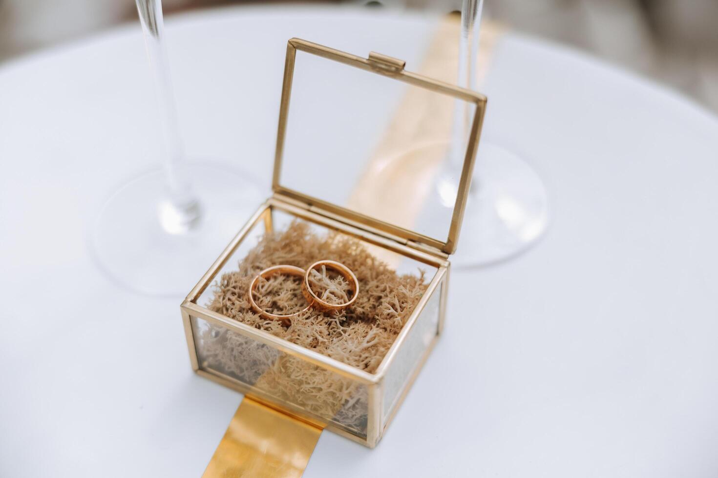 A glass box with gold wedding rings in the middle. Details at the wedding. Wedding ceremony of marriage. photo