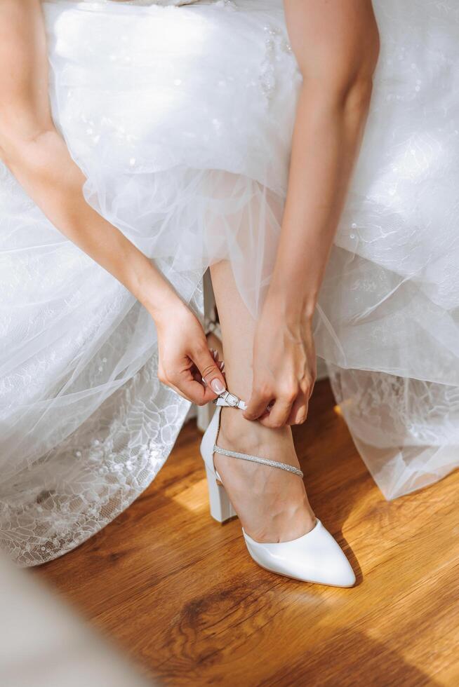 Bride's shoes. The girl wears stilettos. Elegant women's shoes. Beautiful details. The bride puts on her shoes and prepares for the wedding ceremony photo