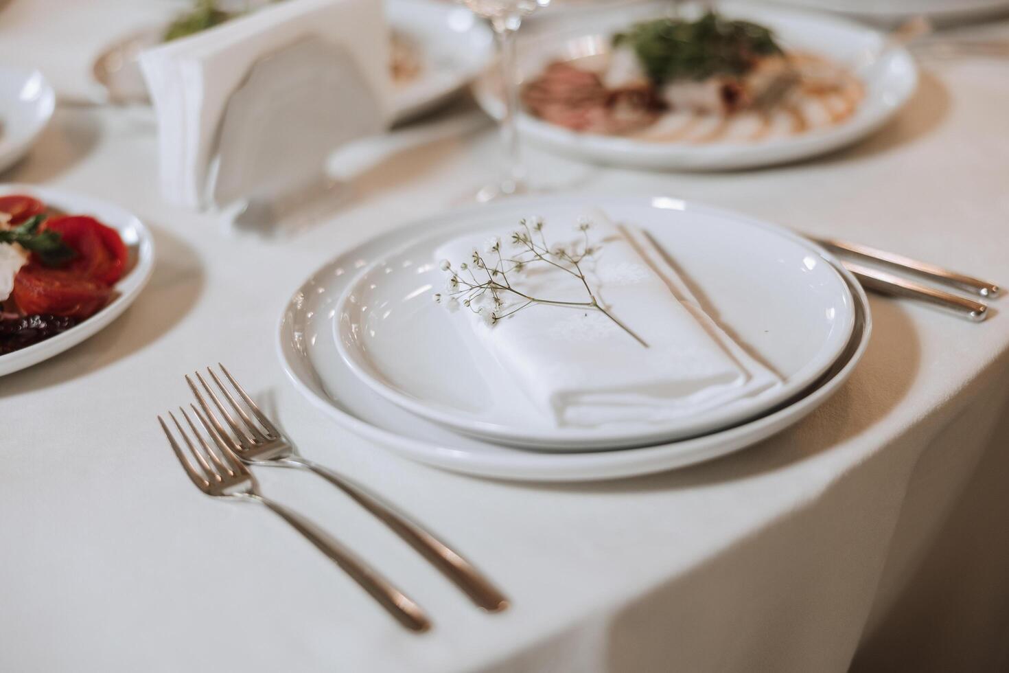 A view of wedding tables, attention to serving, with flower arrangements, expensive cutlery, plates with white napkins. photo