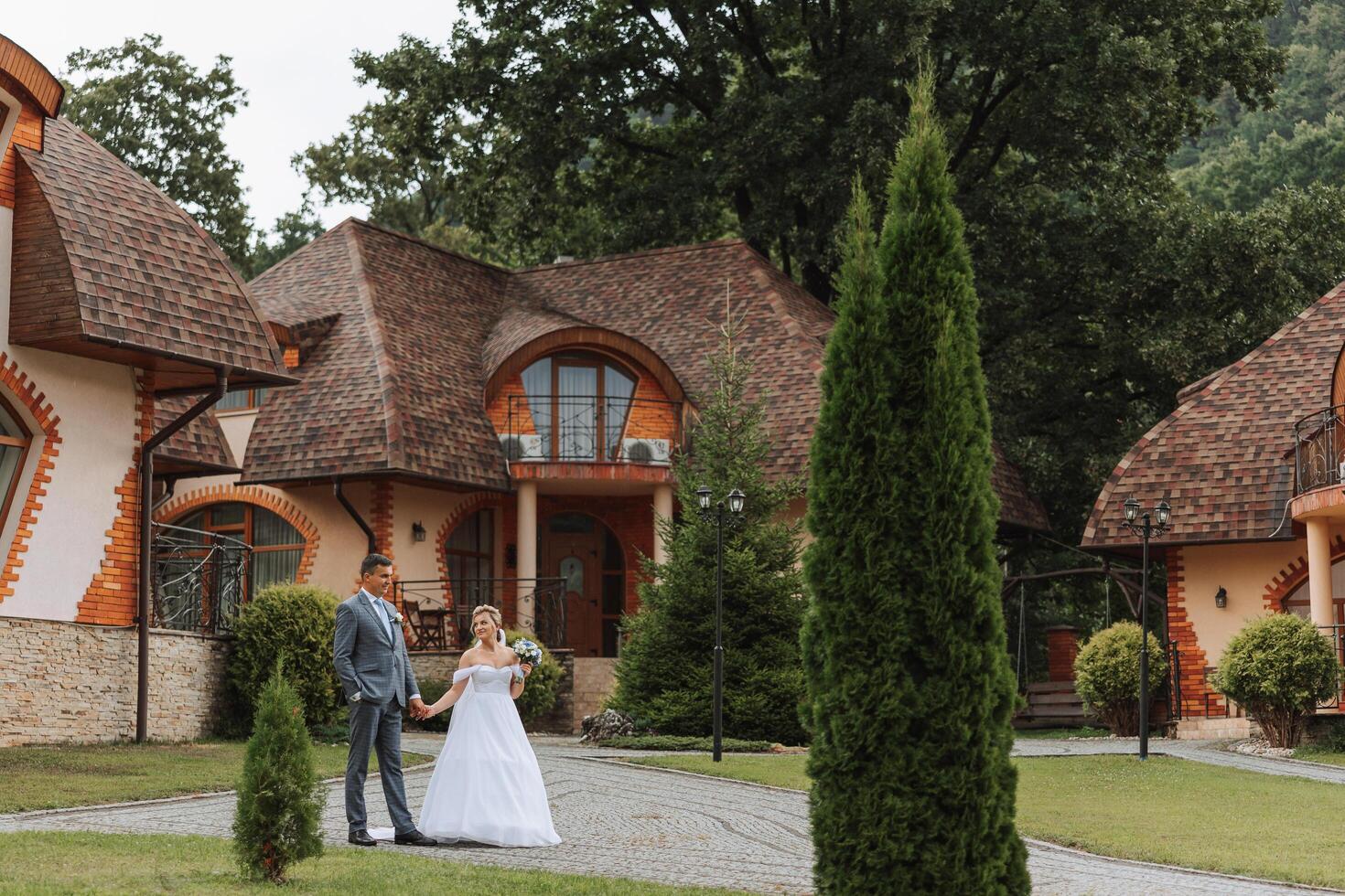 A handsome groom and an elegant bride in a lush white dress are walking in a summer park. Happy bride and groom getting ready for their best day. photo