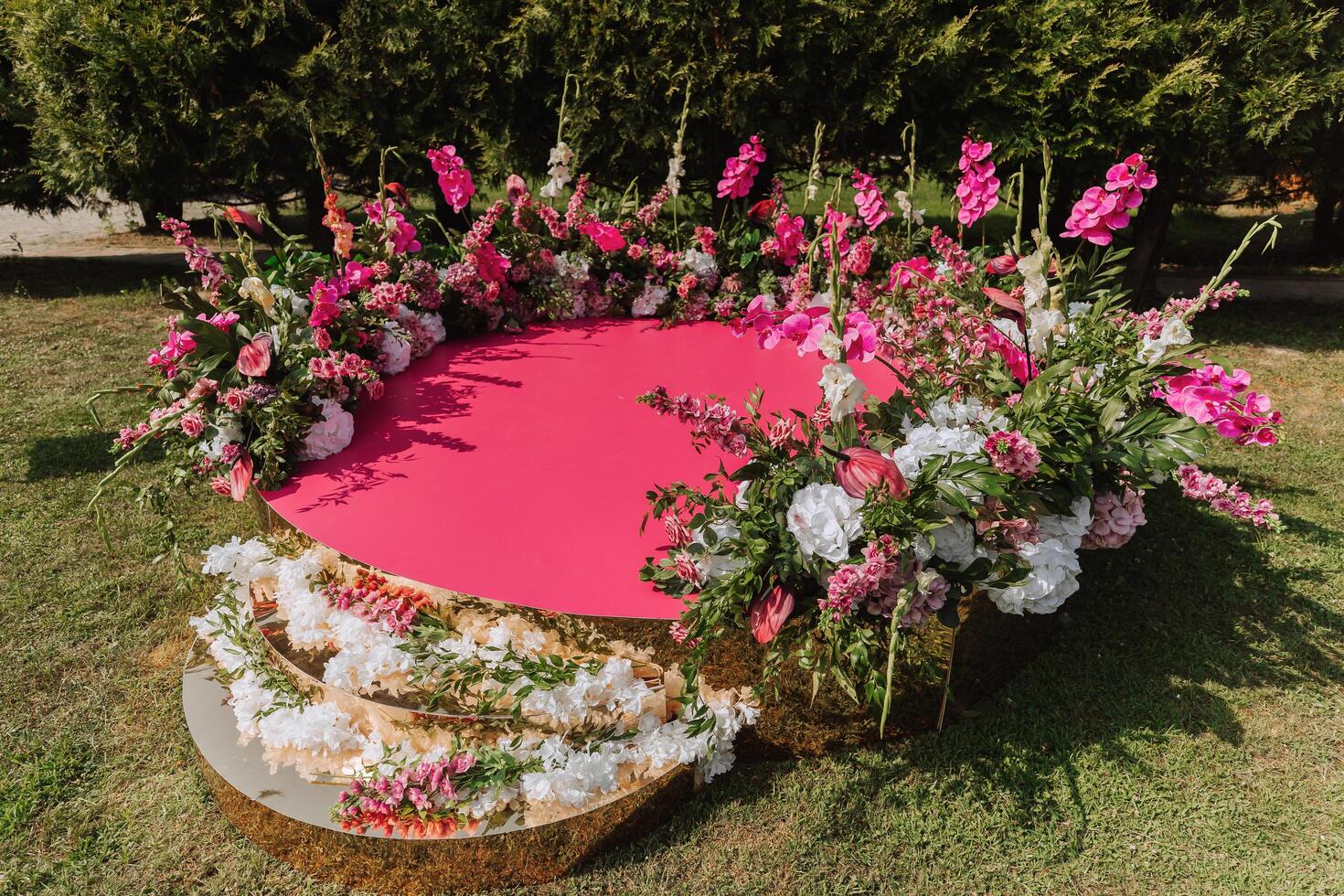 The pink stage is decorated with flowers on the background of the forest. Preparation for the wedding ceremony photo