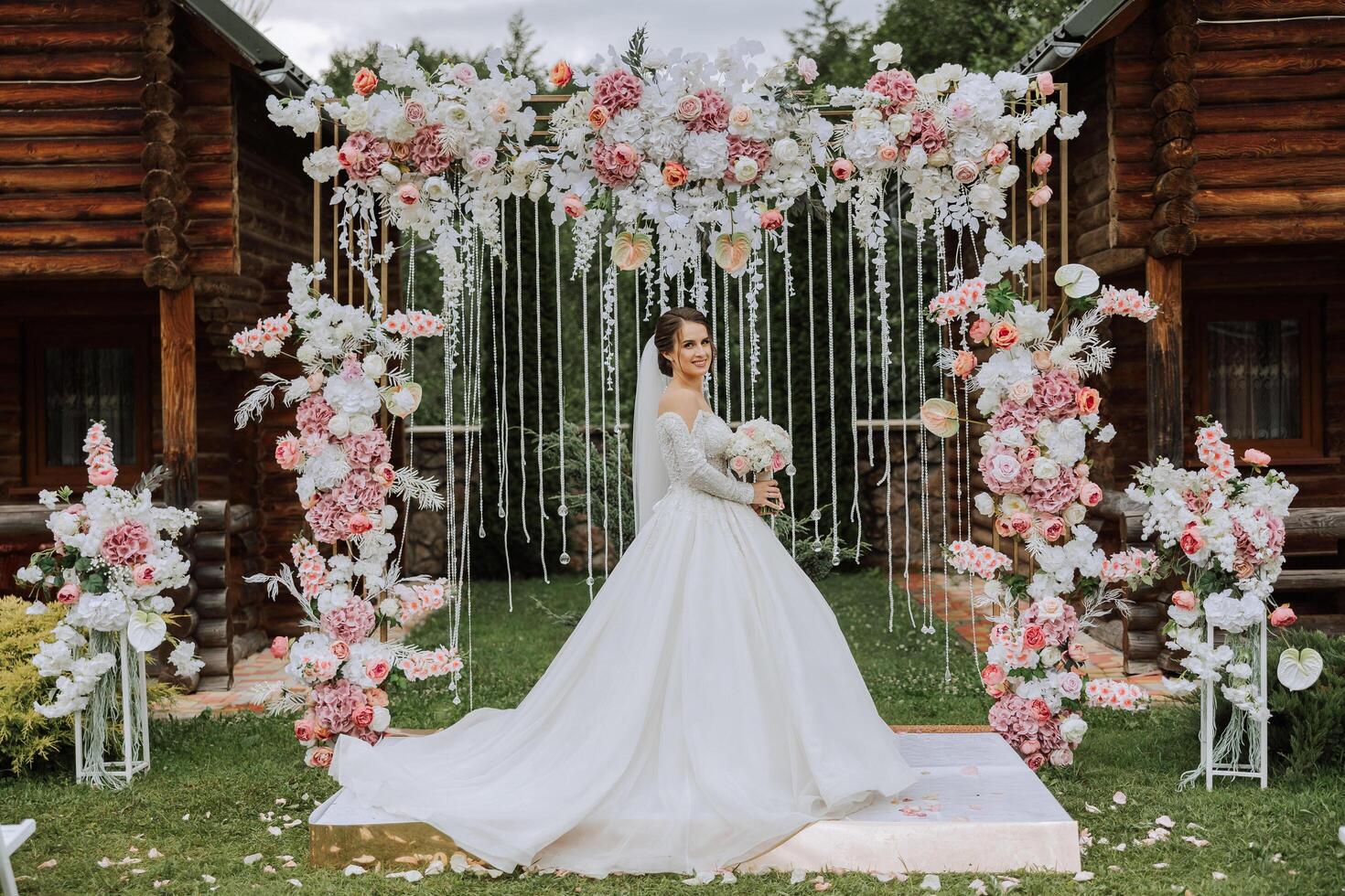 portrait of a beautiful young bride in a white dress with a long train with a long veil and a beautiful hairstyle. A smiling bride against the background of a ceremonial arch decorated with flowers. photo