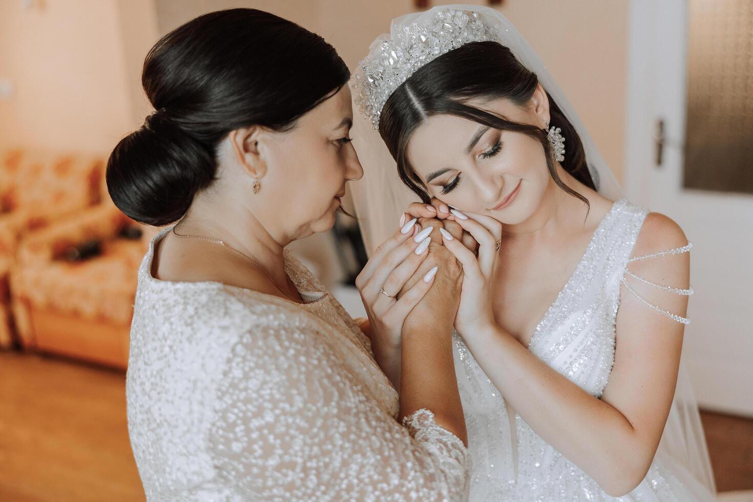 A beautiful and happy mother and her daughter, the bride, are standing next to each other. The best day for parents. Tender moments at the wedding. photo