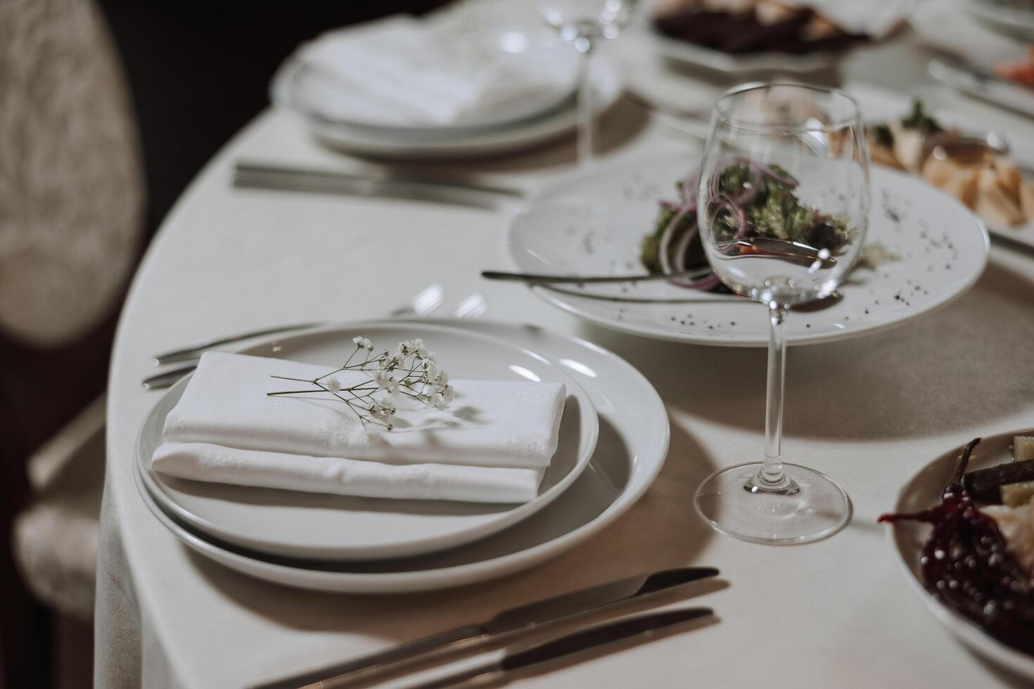 A view of wedding tables, attention to serving, with flower arrangements, expensive cutlery, plates with white napkins. photo