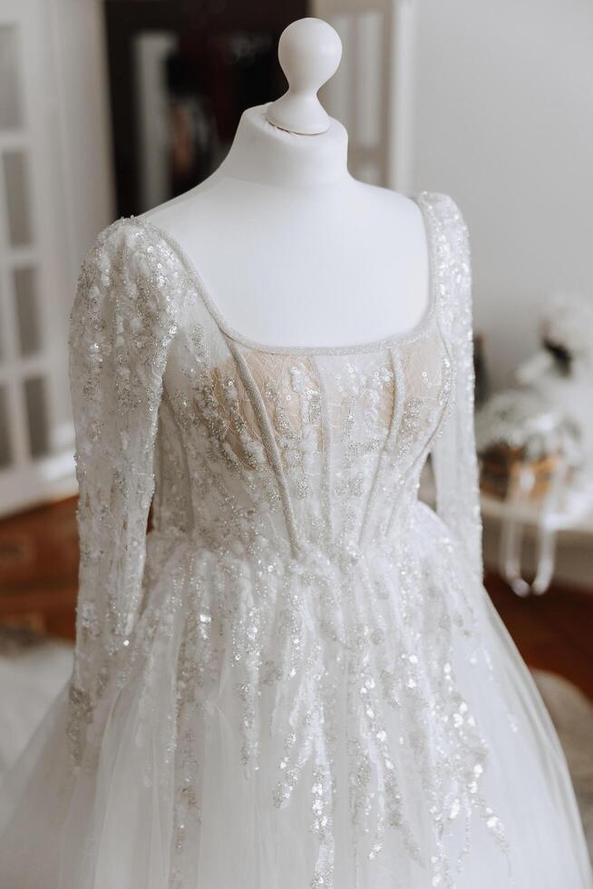 Bedroom interior with wedding dress prepared for the ceremony. A beautiful lush wedding dress on a mannequin in a hotel room. photo