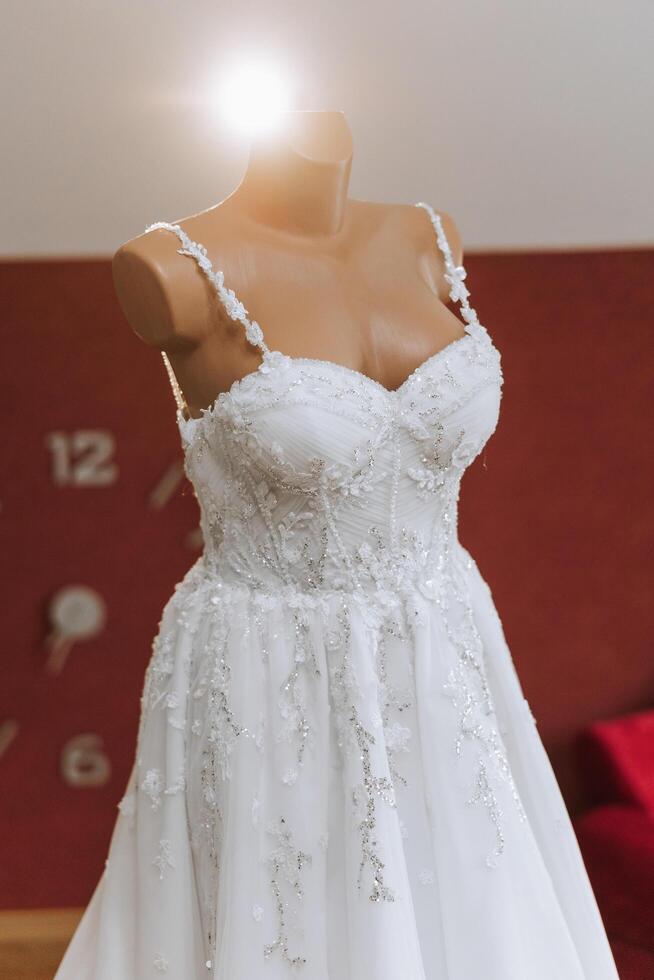 Bedroom interior with wedding dress prepared for the ceremony. A beautiful lush wedding dress on a mannequin in a hotel room. photo