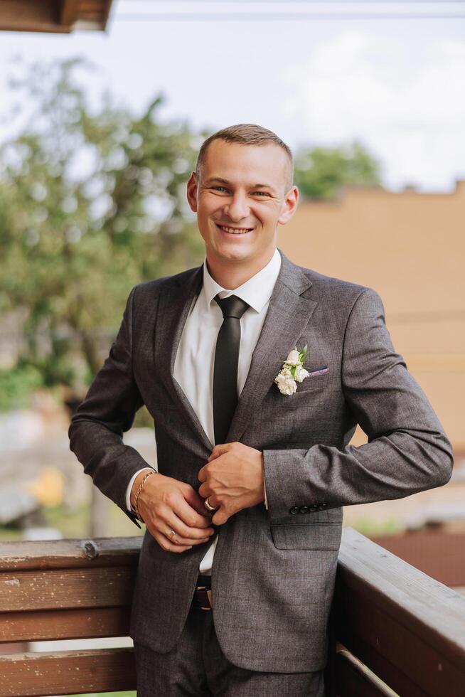 Portrait of the groom in nature in the summer. Stylish tall groom in an elegant gray business suit. Businessman in nature. Portrait of a successful man. Wedding portrait of the groom. photo