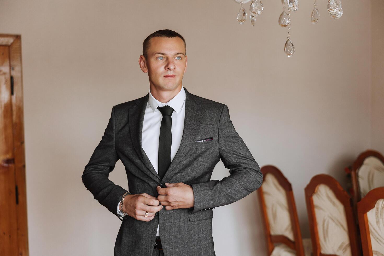 Portrait of a young groom at home before the wedding ceremony. A handsome man dressed in a classic suit. Male portrait. photo