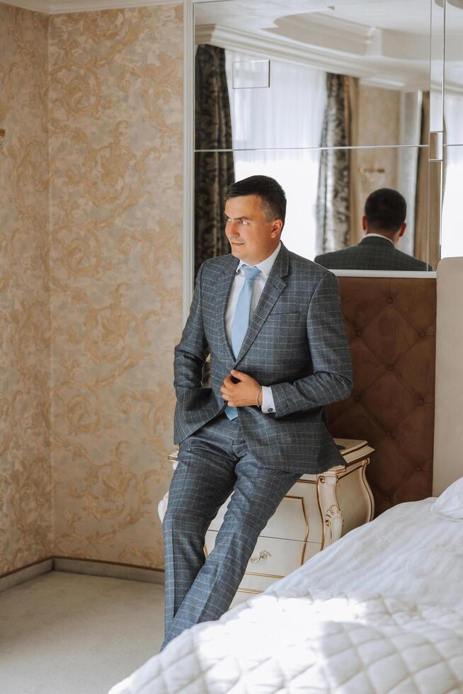 Portrait of a young groom at home before the wedding ceremony. A handsome man dressed in a classic suit. Male portrait. photo