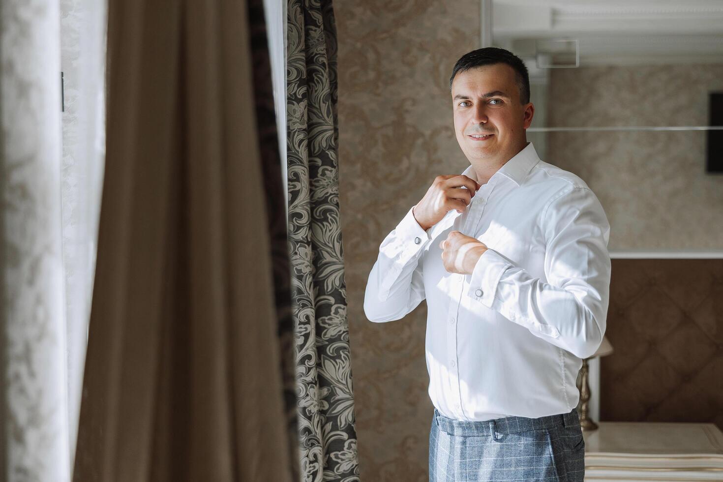 Business shirt. A man in a white shirt fastens the buttons. Young politician, male style, businessman buttoning shirt, male hands close-up, american, european businessman photo