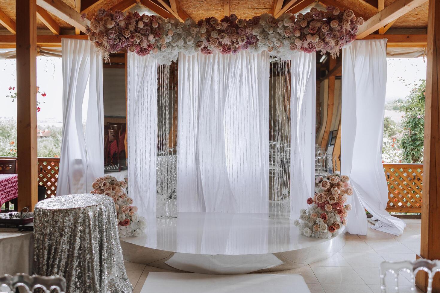 The white arch is decorated with pink flowers. White carpet and white chairs. Preparation for the wedding ceremony photo