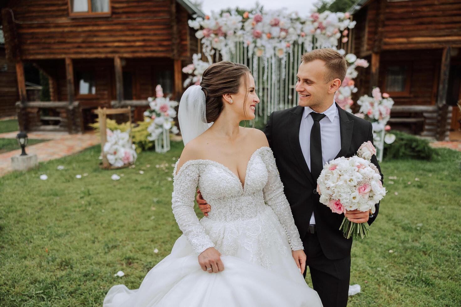 A handsome groom and an elegant bride in a lush white dress are walking in a summer park. Happy bride and groom getting ready for their best day. photo