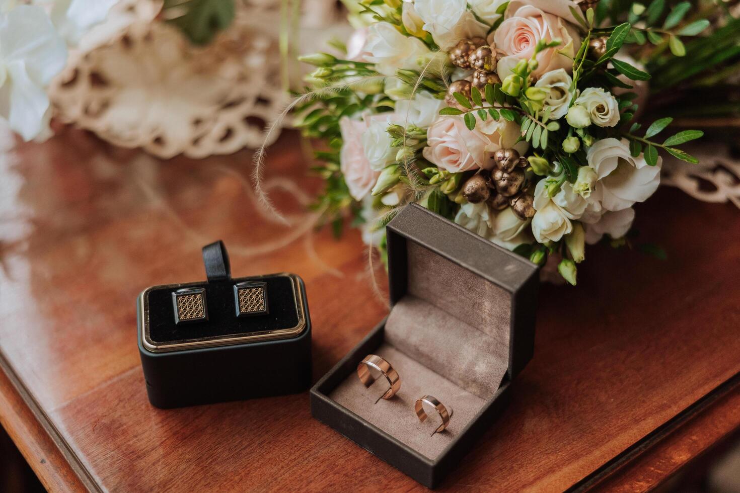 On the floor are men's dark leather shoes and a black belt, a man's suit on a mannequin, a wedding bouquet of flowers, wedding rings, men's perfume. Photo, top view. photo