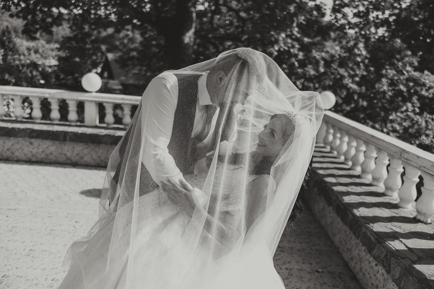 Close-up portrait of two people in love. An affectionate groom embraces the bride, supporting her under the veil. The best moments of the wedding. photo