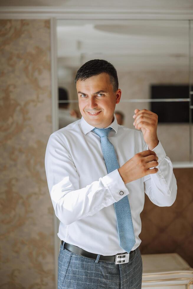 Business shirt. A man in a white shirt fastens the buttons. Young politician, male style, businessman buttoning shirt, male hands close-up, american, european businessman photo