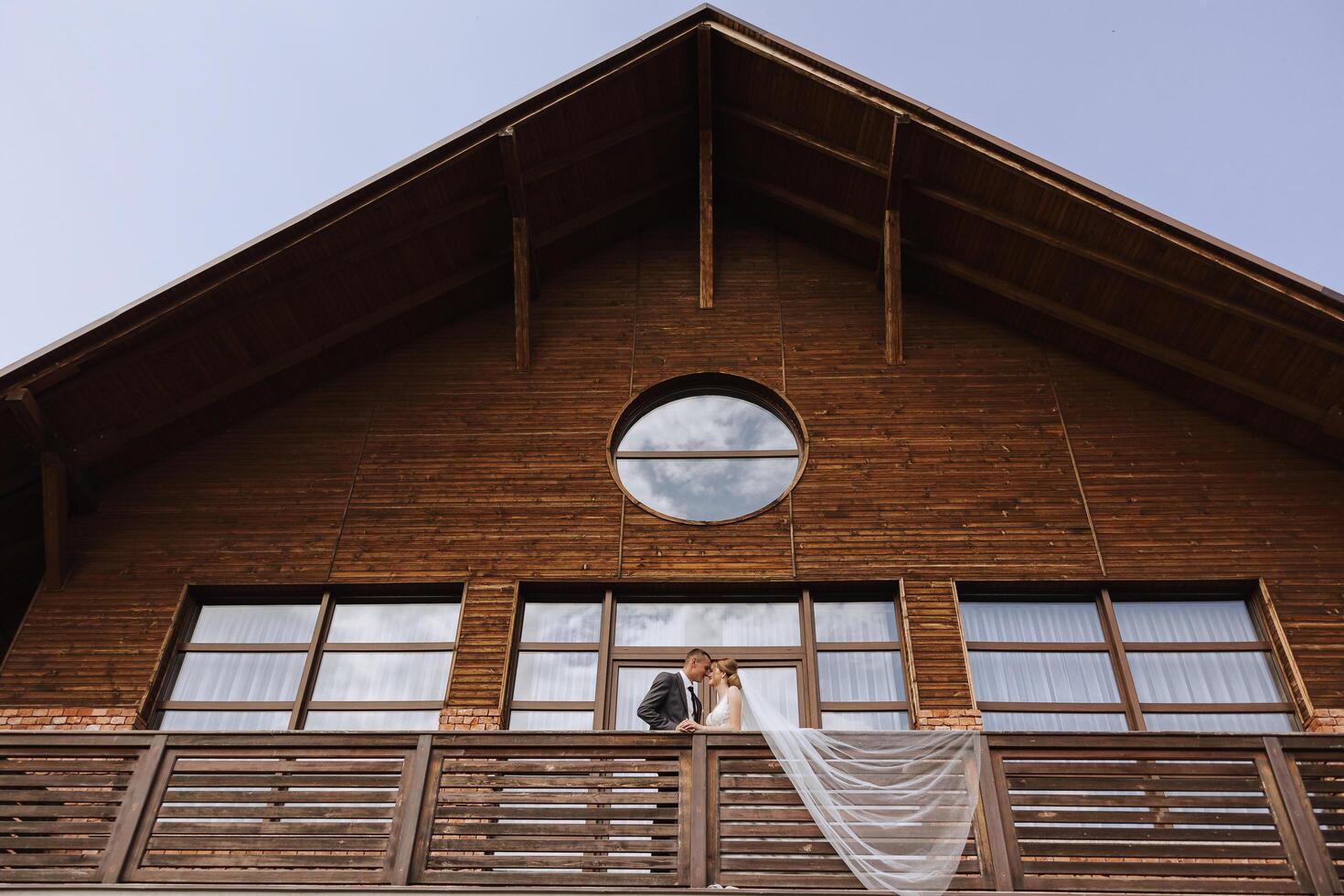 un recién casado Pareja. el viento ascensores un largo blanco velo en verano. el novia y novio son abrazando, un largo velo es soplo en el viento. el recién casados Beso en el balcón de el restaurante foto