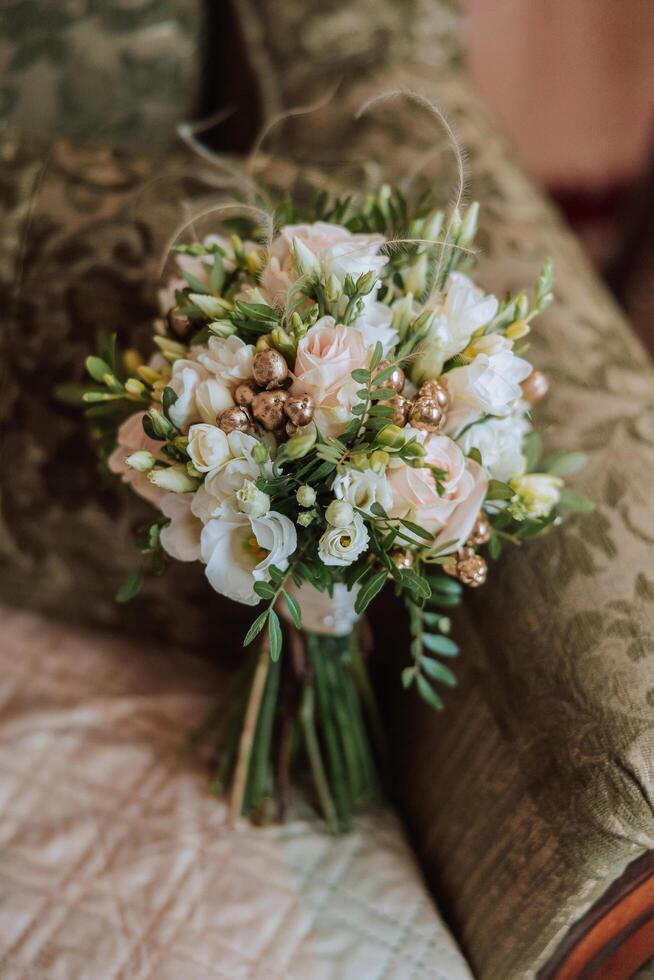 Wedding bouquet. White cut roses, green seed heads and leaves. Green stems and white ribbon and gold wedding rings. photo