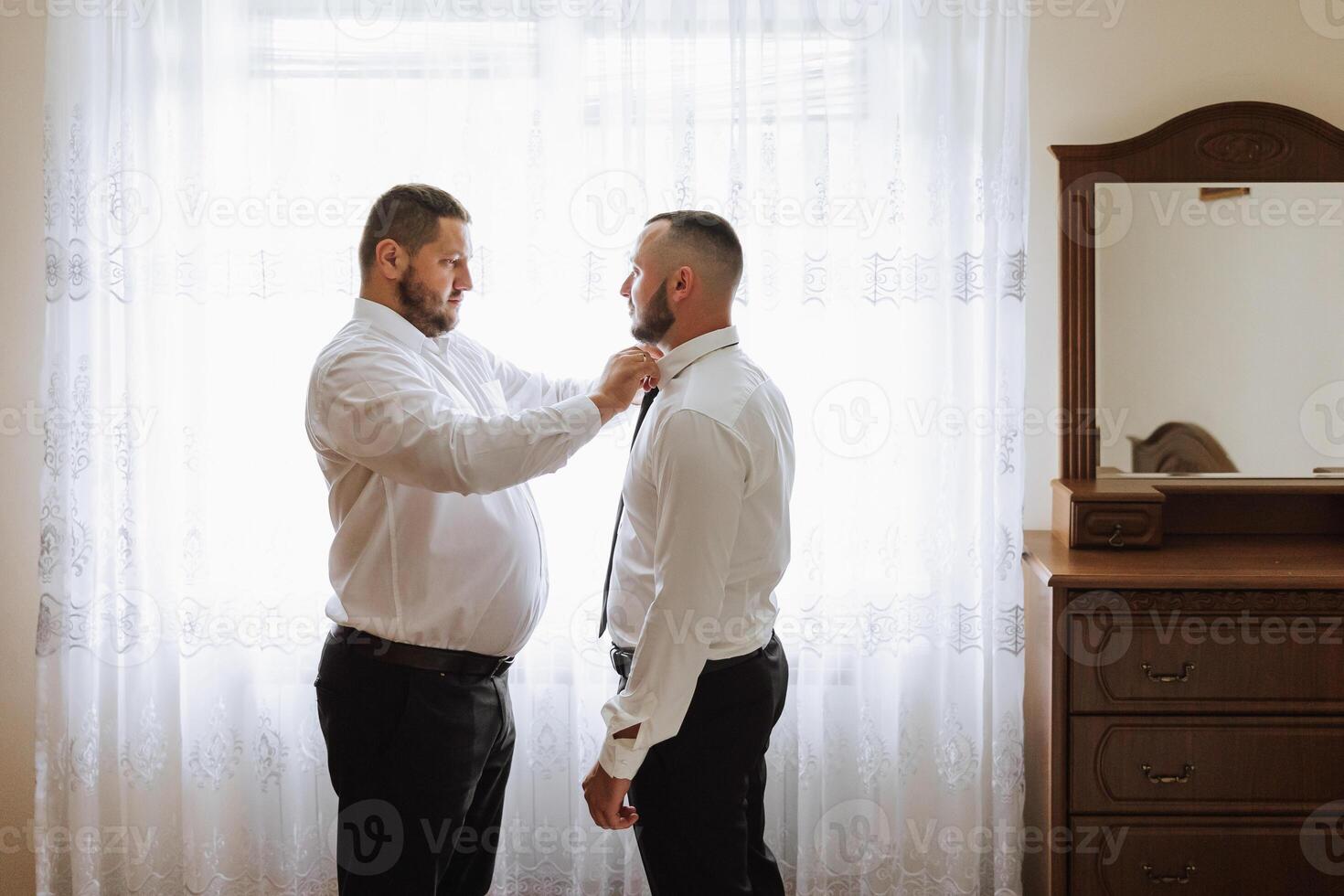 stylish groom laughing and having fun with groomsmen while getting ready in the morning for wedding ceremony. luxury man photo