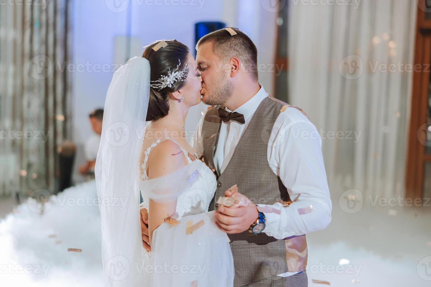 Wedding dance of the bride and groom. The first dance of the bride and groom in an elegant wedding hall with the use of heavy smoke and pyrotechnic lights, confetti. photo