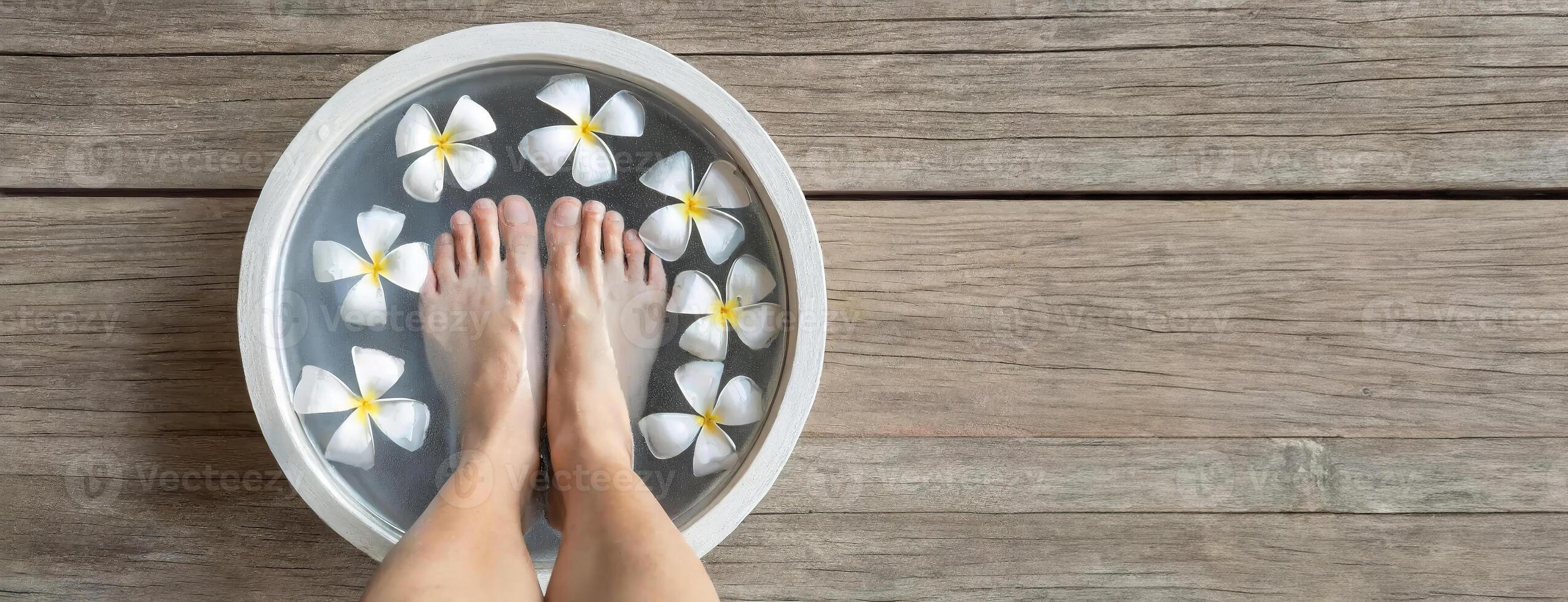 AI Generated Feet soaking in a bowl with plumeria flowers, self-care ritual. A tranquil spa setting with a wooden background enhancing the relaxation vibe. photo