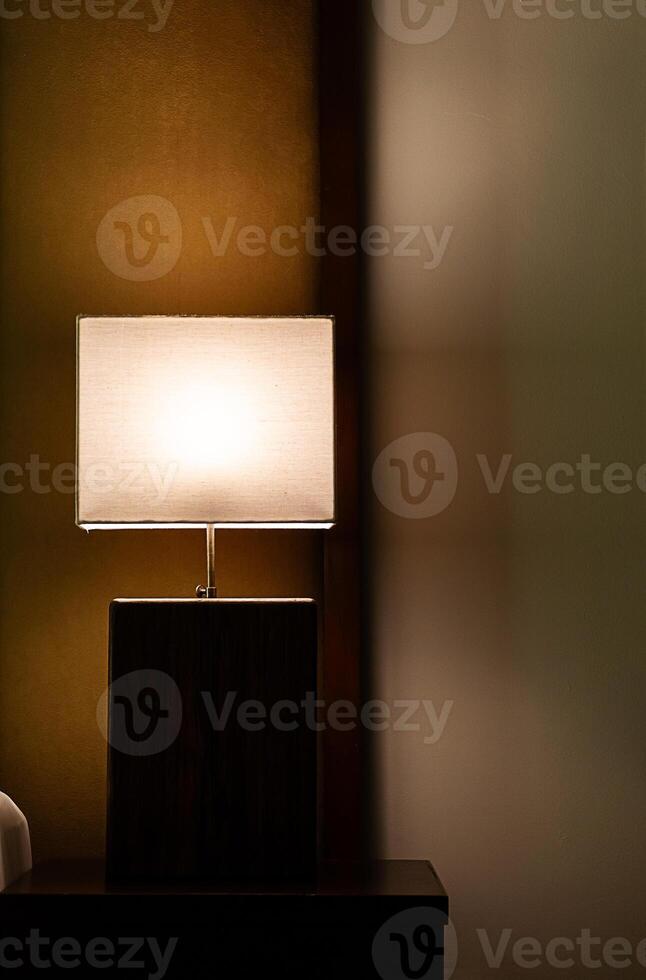 Glowing lamp on nightstand In the evening. photo