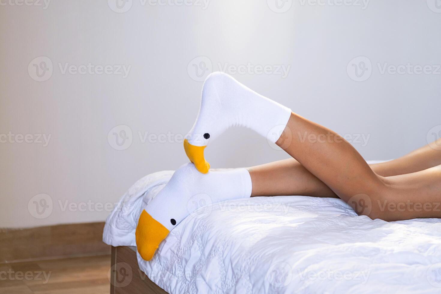 Unrecognizable female in funny socks relaxing on bed at home. photo