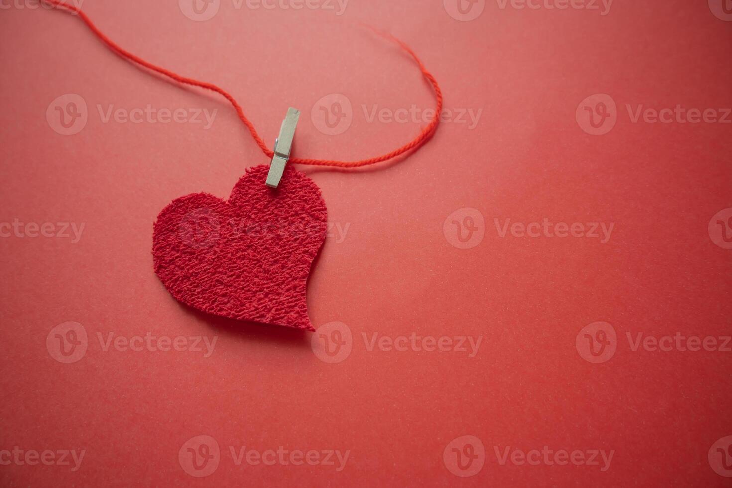 hermosa corazón en papel retenida por un rojo hilo con un corchete. foto
