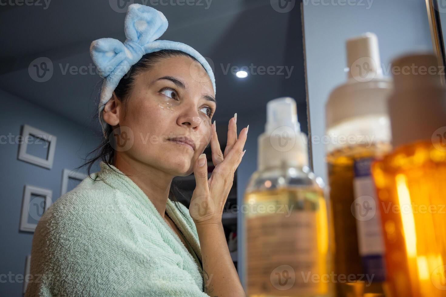 Latin woman applies refreshing eye cream in her room at night. photo