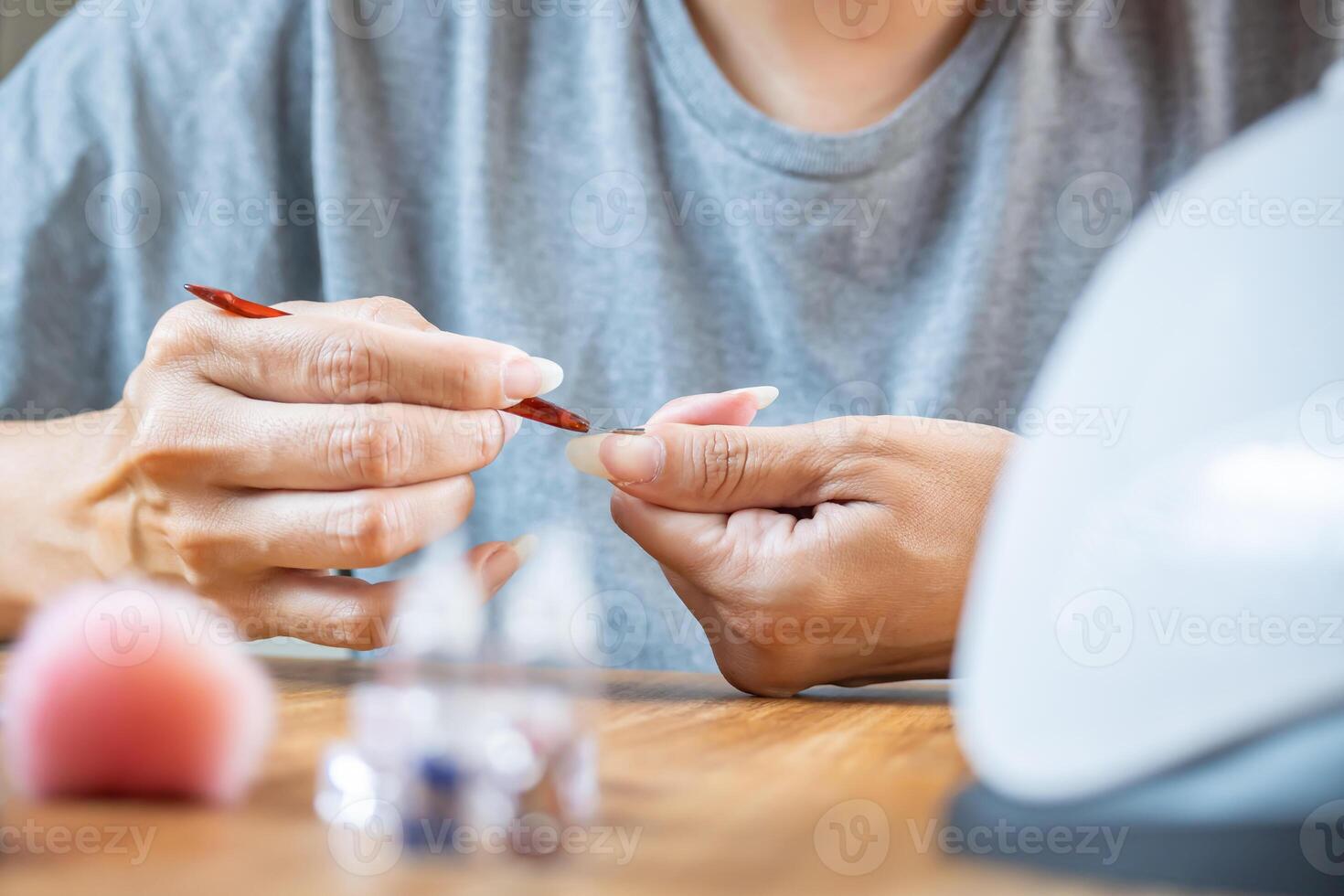 Woman using a cuticle remover on her hands. photo