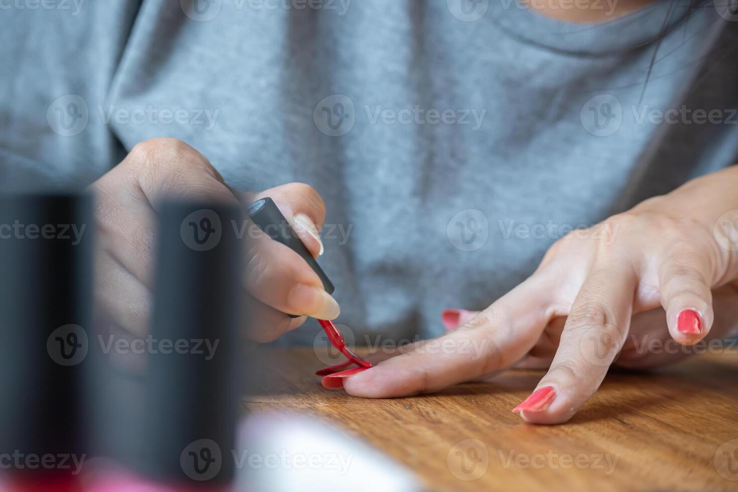 Woman paints her nails on the kitchen table. She uses semipermanent nail polishes. photo