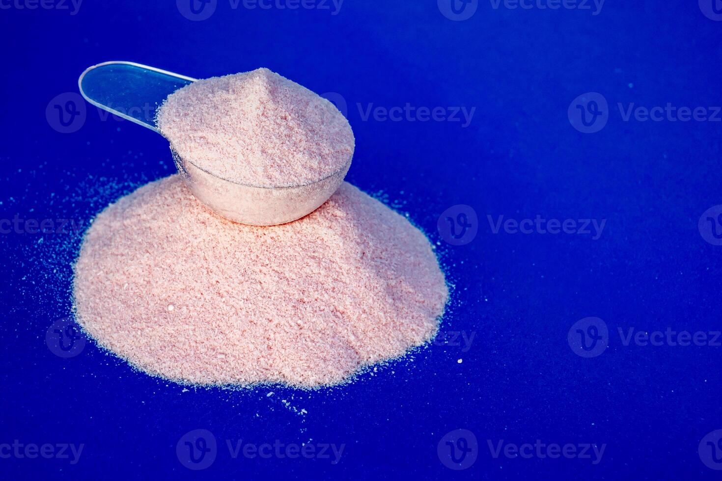 Strawberry creatine scoop on a blue background. photo