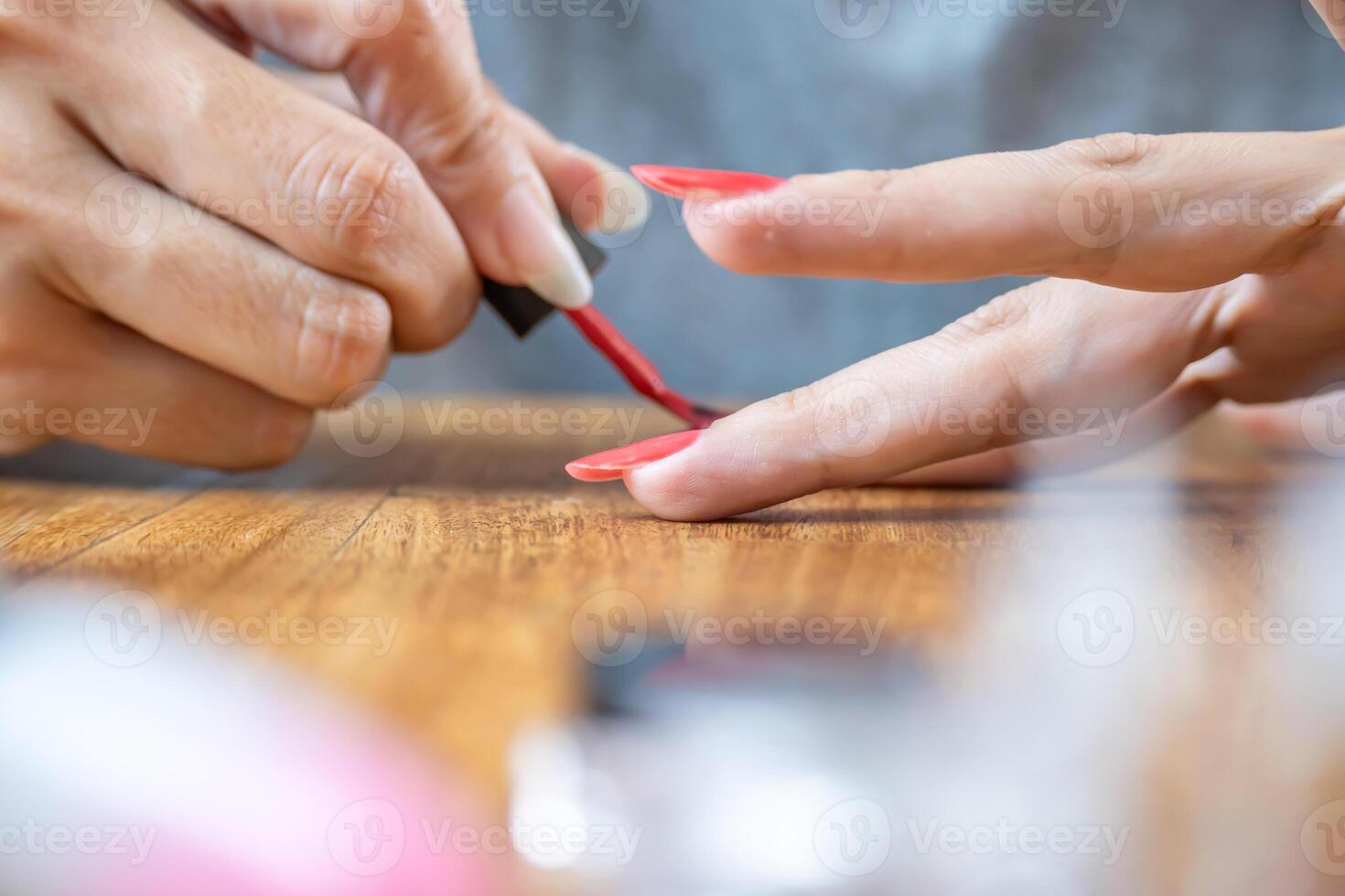 Close up photo of woman's hands painting her nails red.