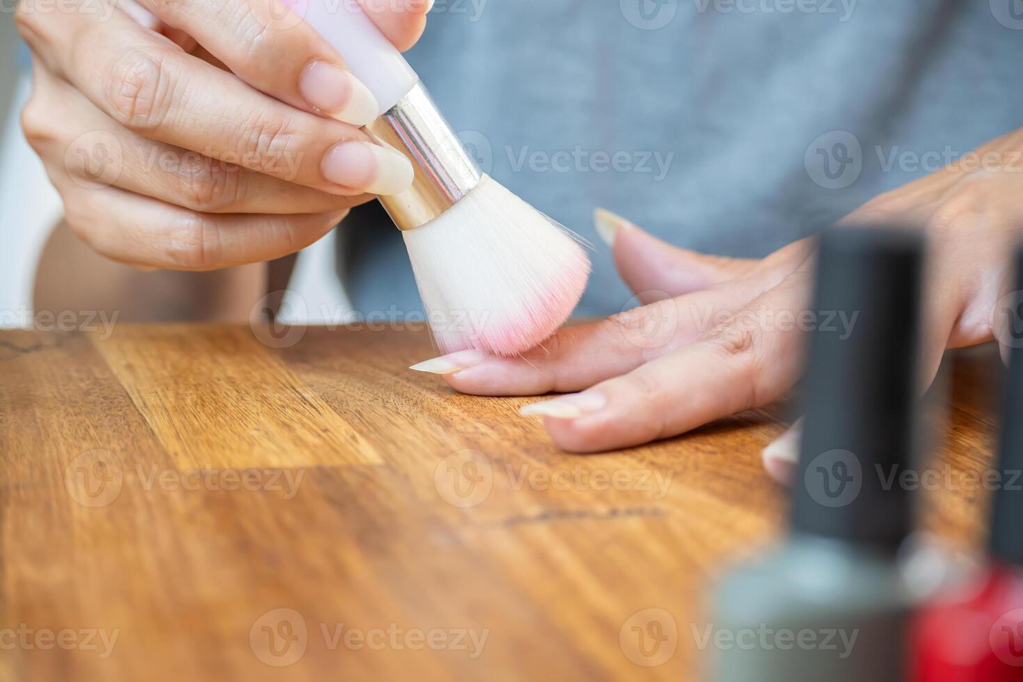 Woman cleaning her nails after filing the top before applying semi-permanent nail polish. photo