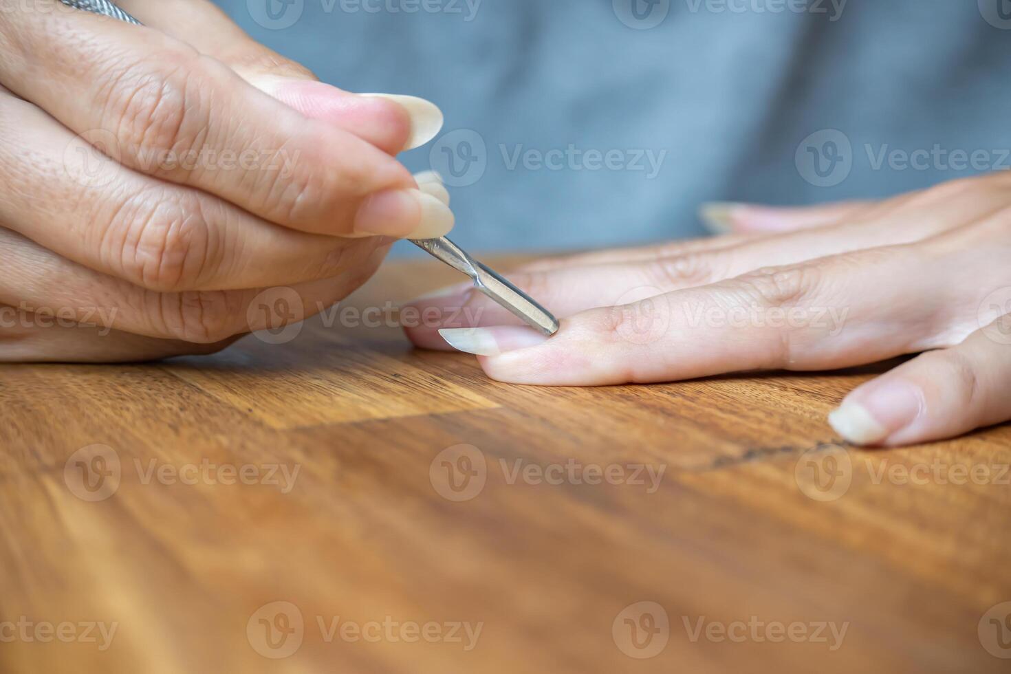 Woman's fingers using a paddle-shaped cuticle pusher. photo