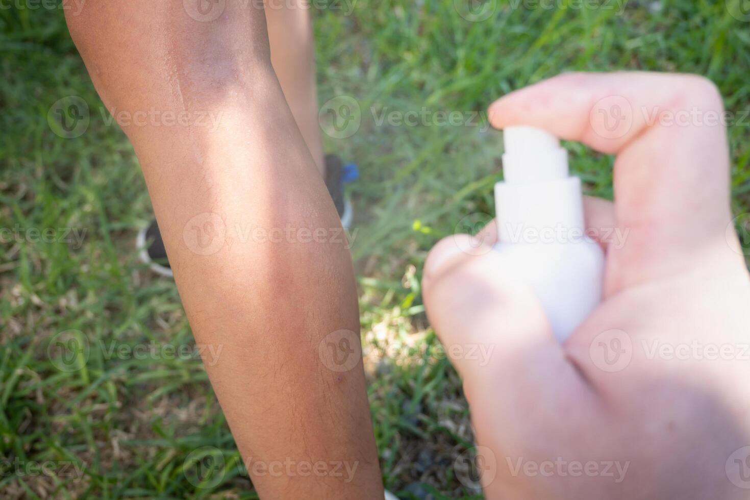 Hand of a father putting sunscreen on his son's leg. photo