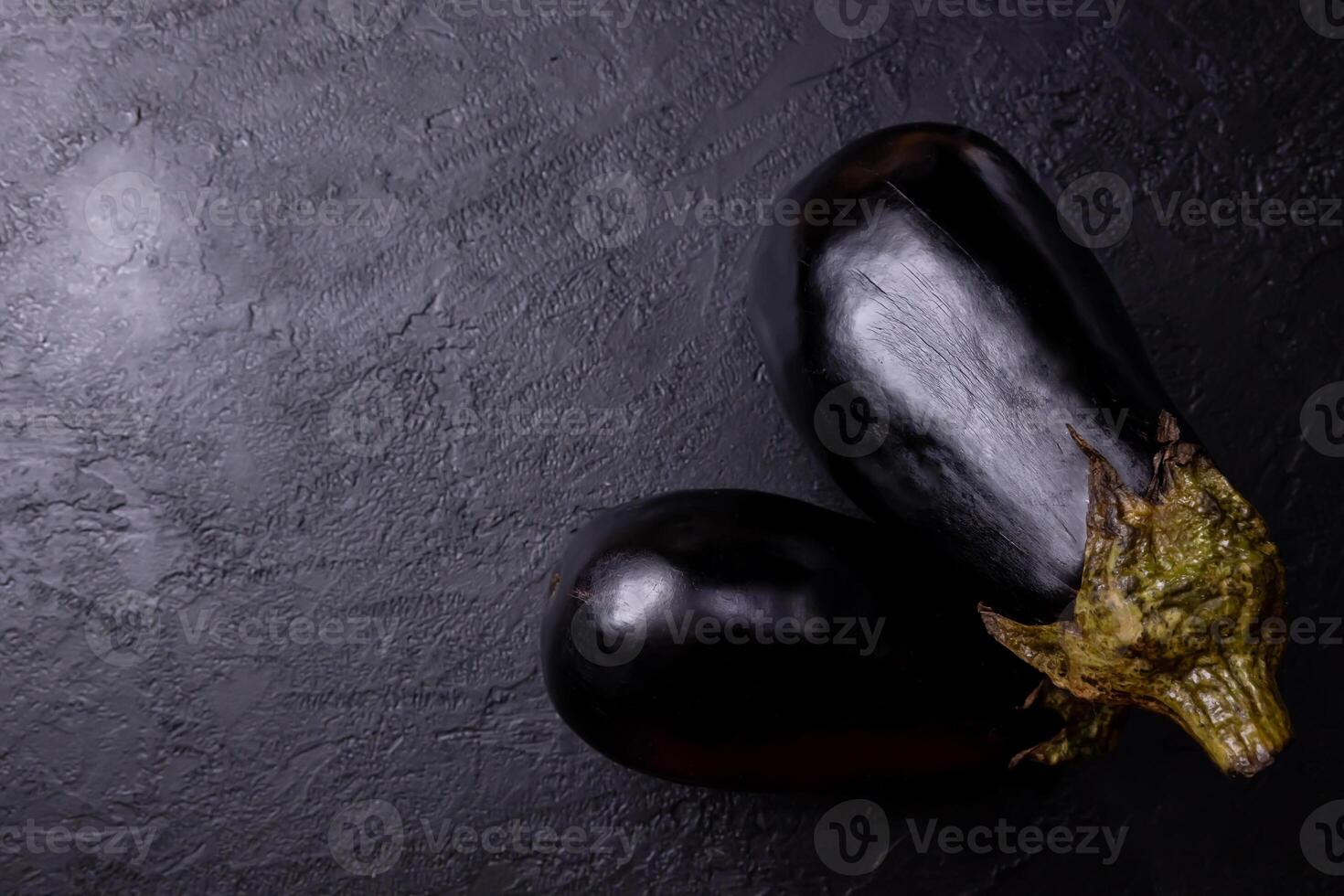 Eggplants on a black table, with low lighting. photo