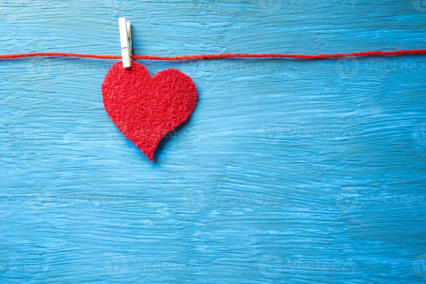 corazón colgando con un pinza para la ropa, en un ligero azul antecedentes. foto