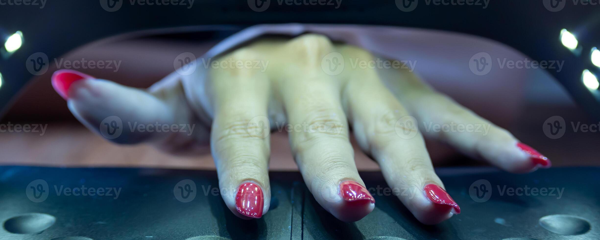 Hands of a woman inside the UV booth for semi permanent nails. photo