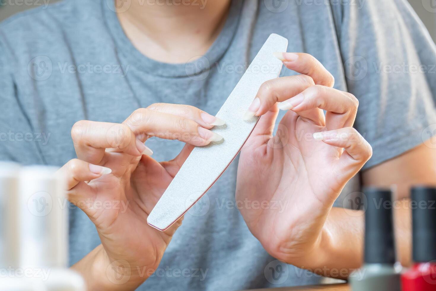 Woman's hands filing their nails to clean up imperfections before starting to apply the polish. photo