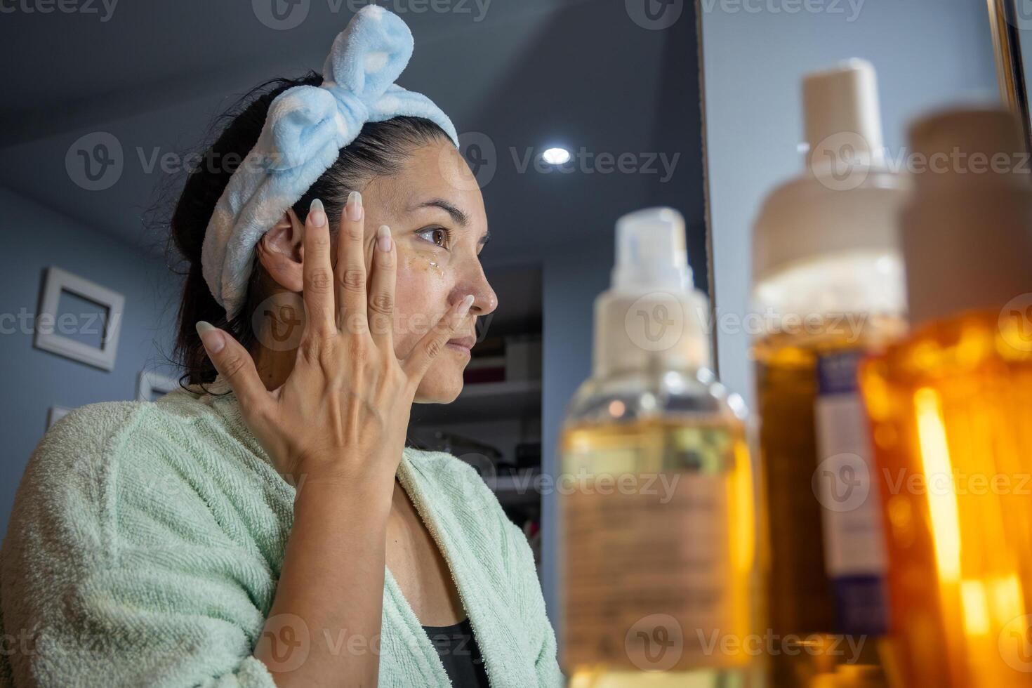 Latin girl applies cosmetics at night in front of the mirror. photo