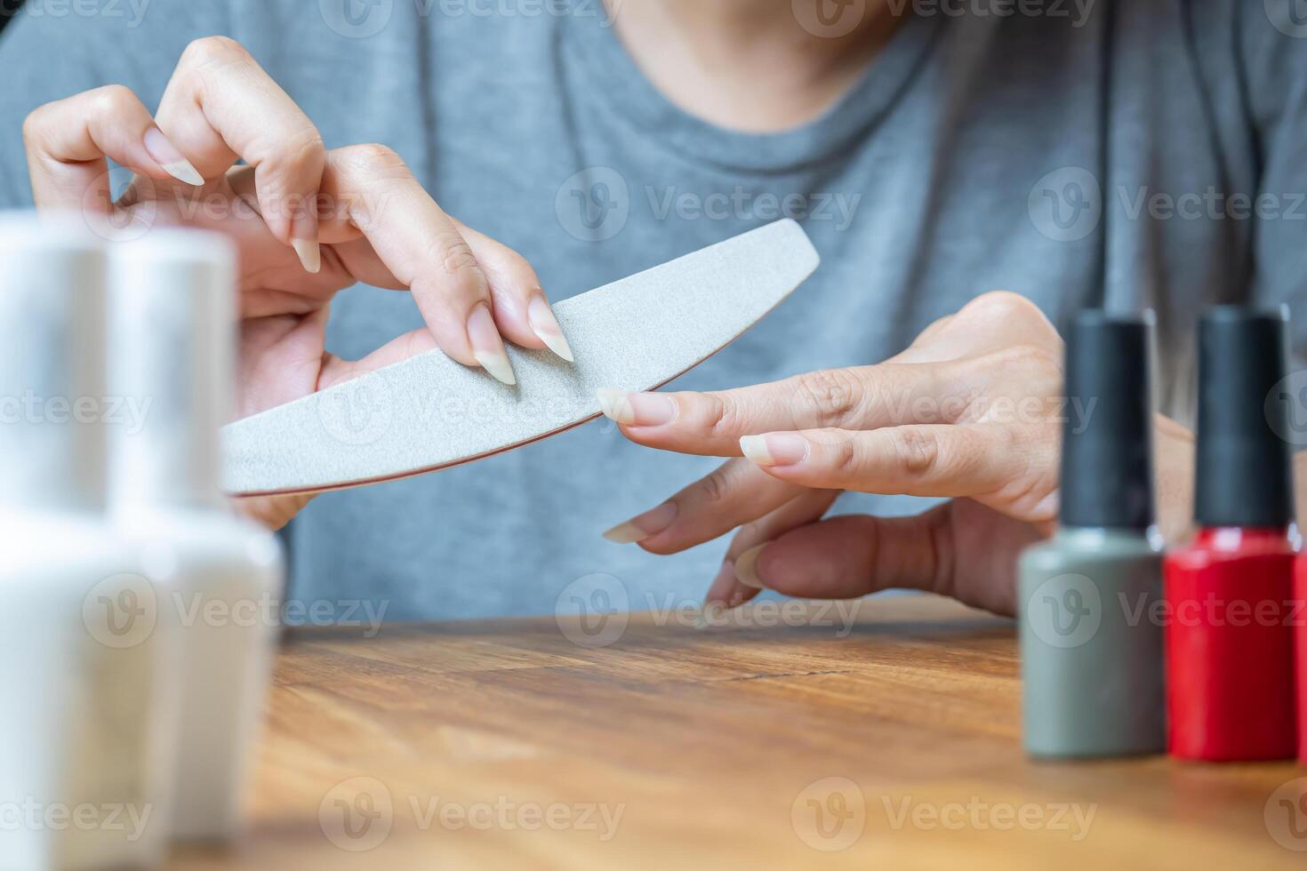 Woman using file to shape nails. Nail treatment before applying polish. photo