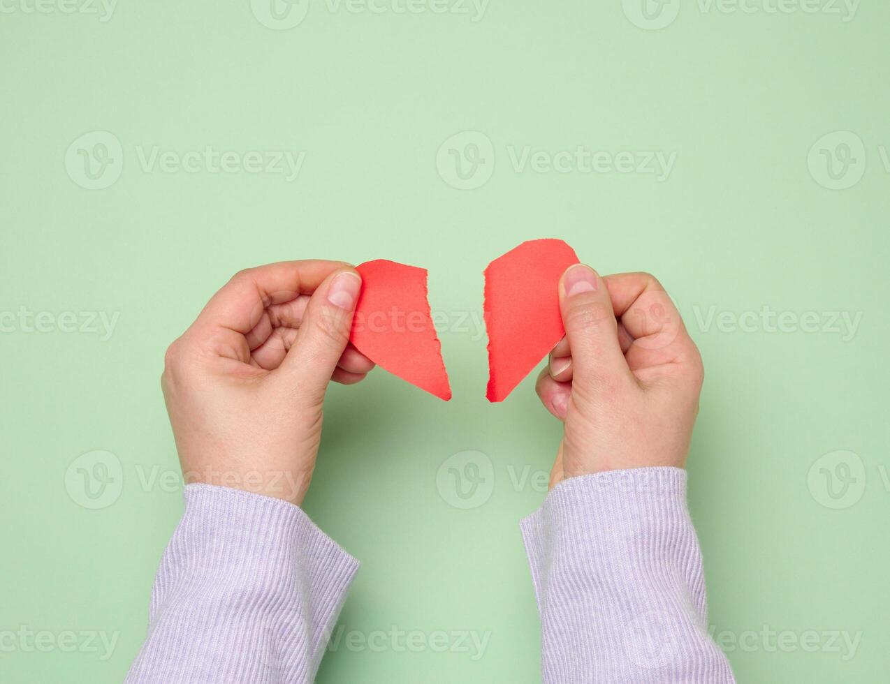 Two female hands tearing a red paper heart, symbolizing divorce photo