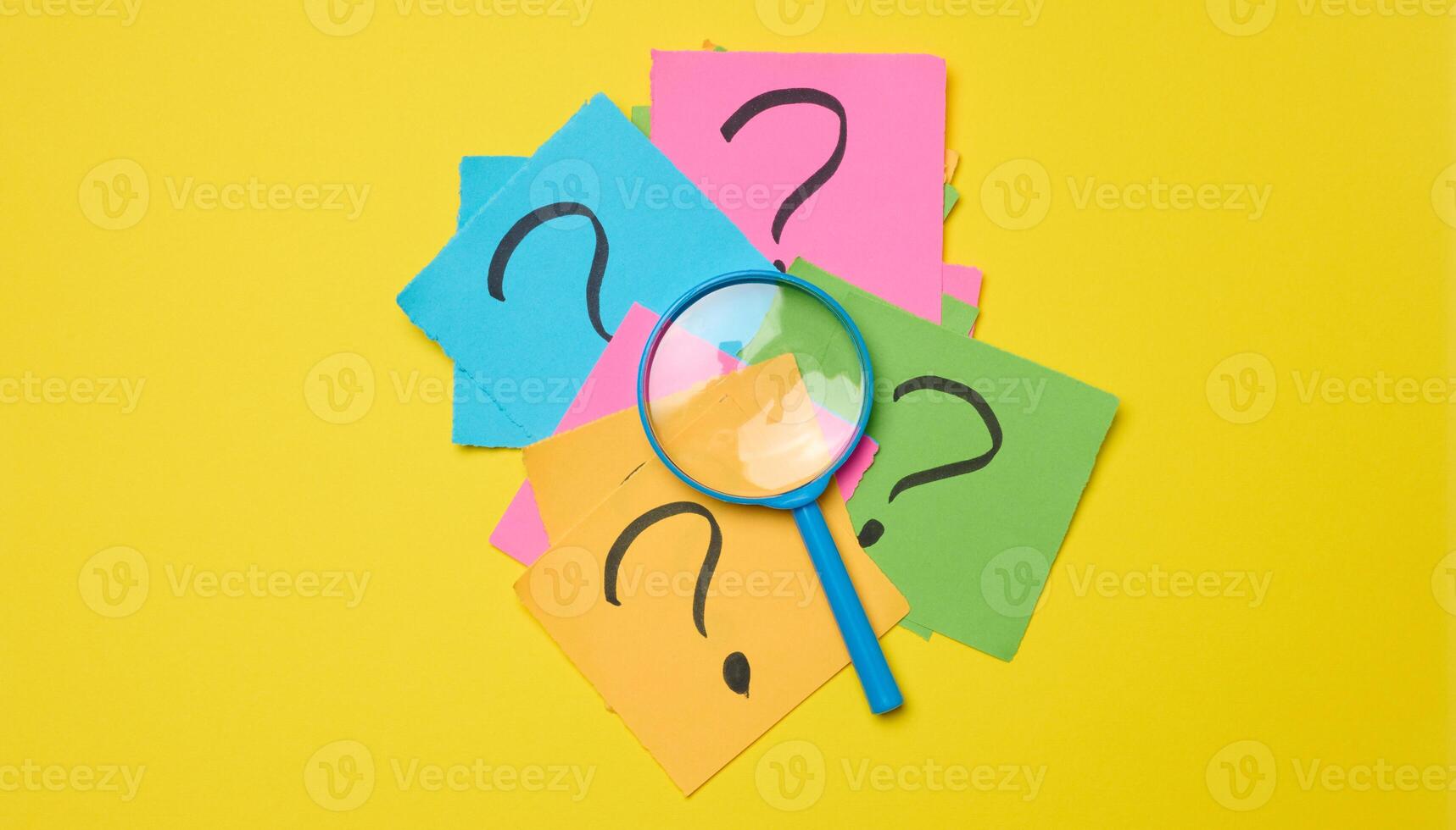 Drawn question marks on stickers and a magnifying glass, yellow background. photo