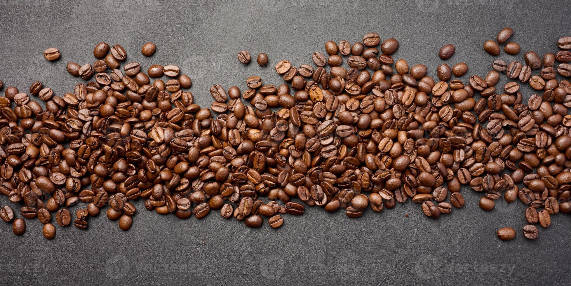 Scattered roasted coffee beans on black background, top view photo