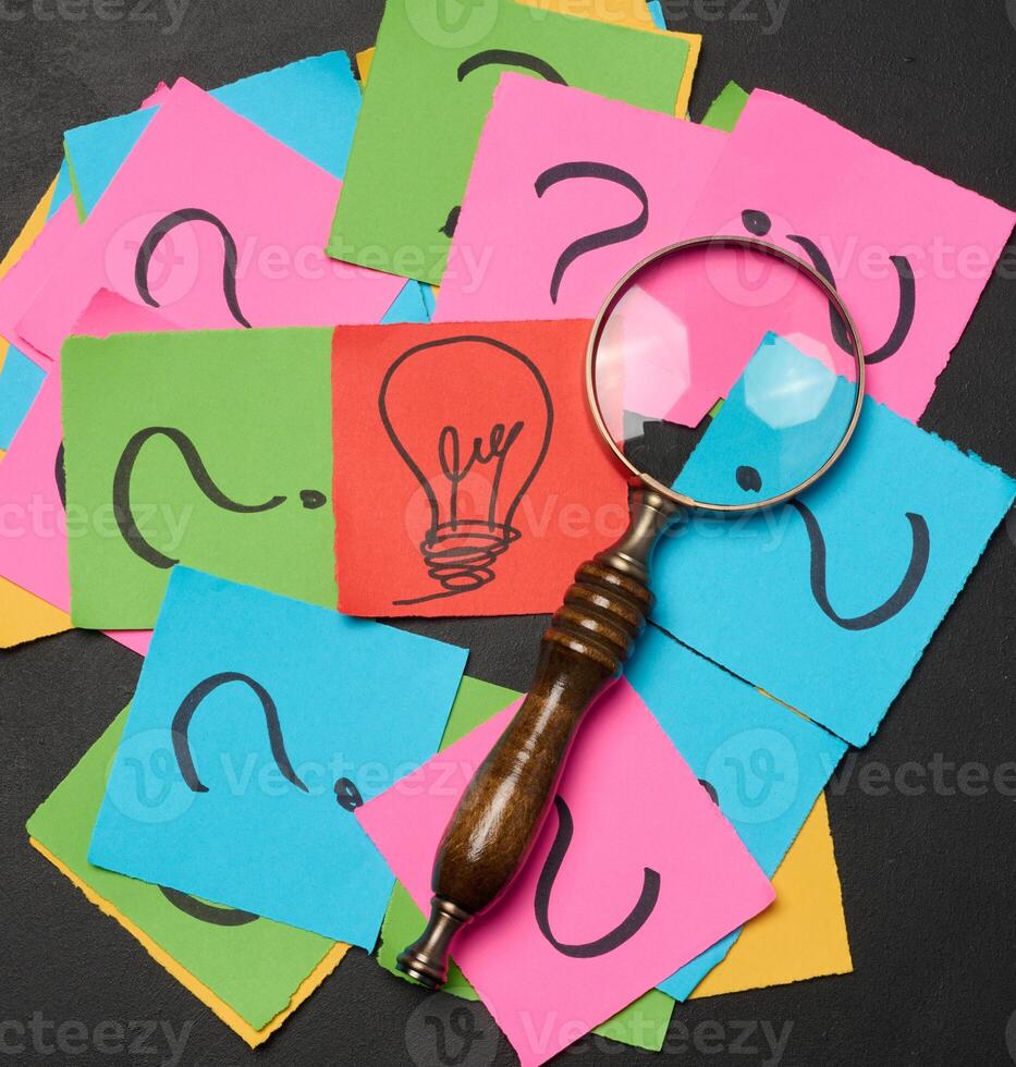 Drawn light bulbs on sheets of paper and a magnifying glass photo